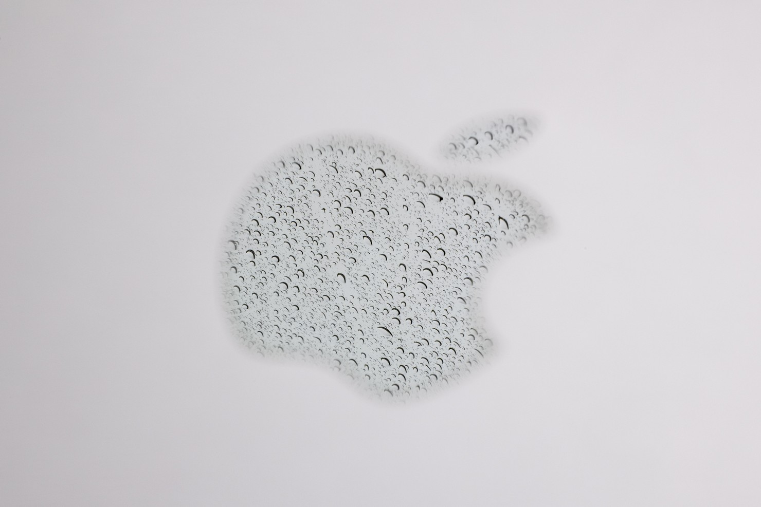A reflection of rain in the Apple logo on a laptop