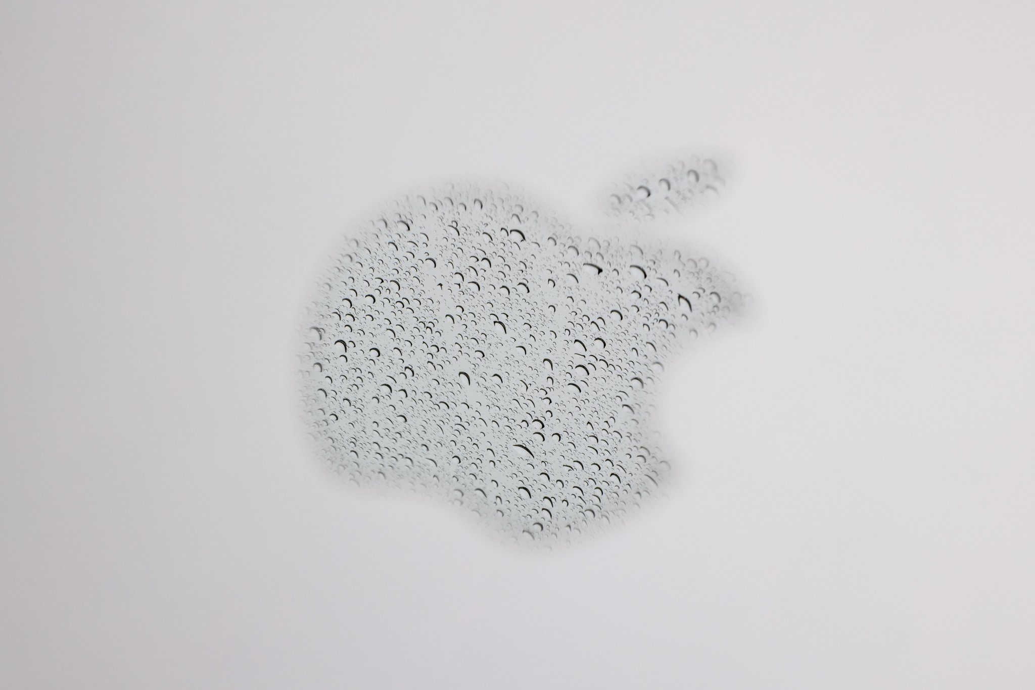 A reflection of rain in the Apple logo on a laptop photographed at f/20