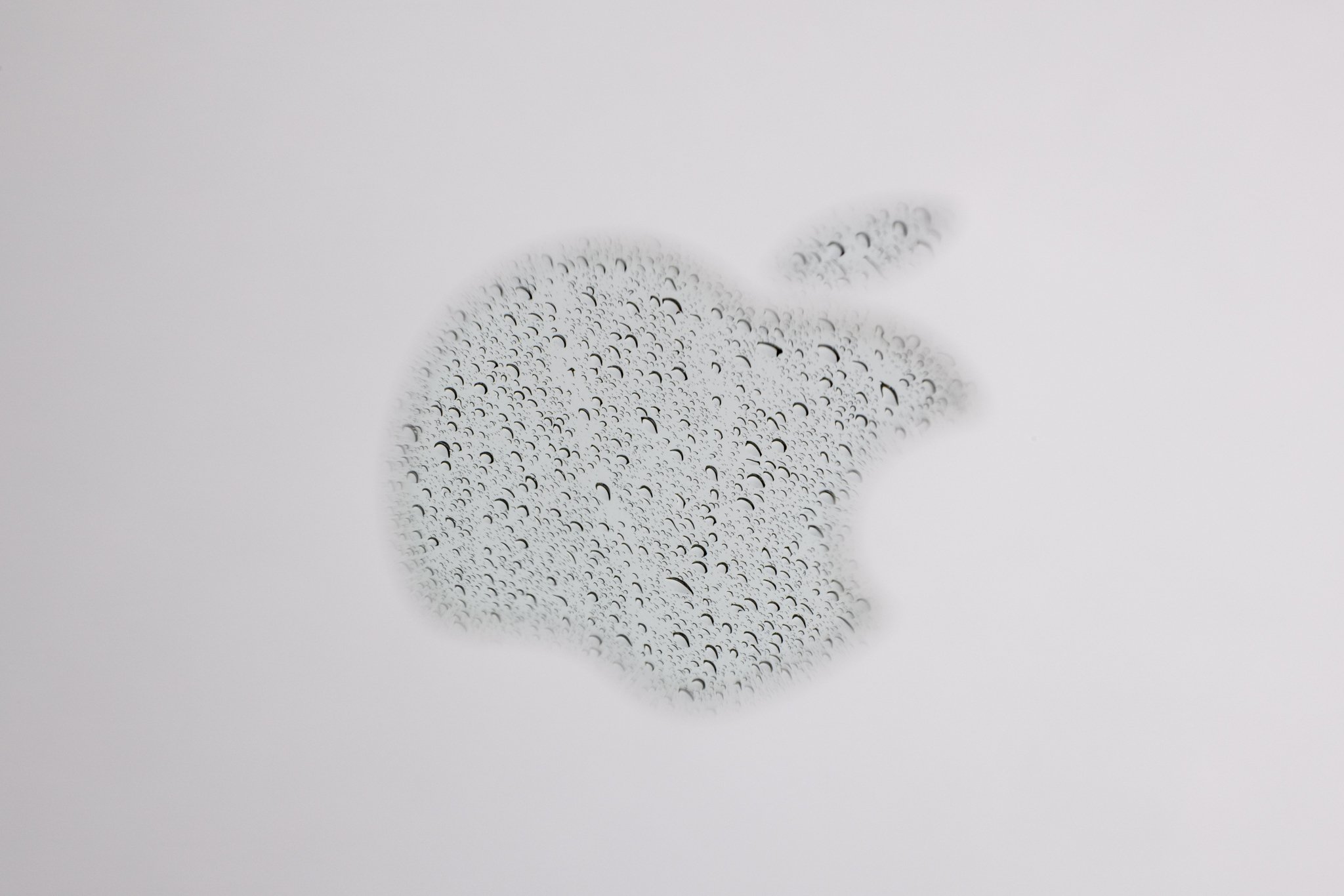 A reflection of rain in the Apple logo on a laptop photographed at f/22
