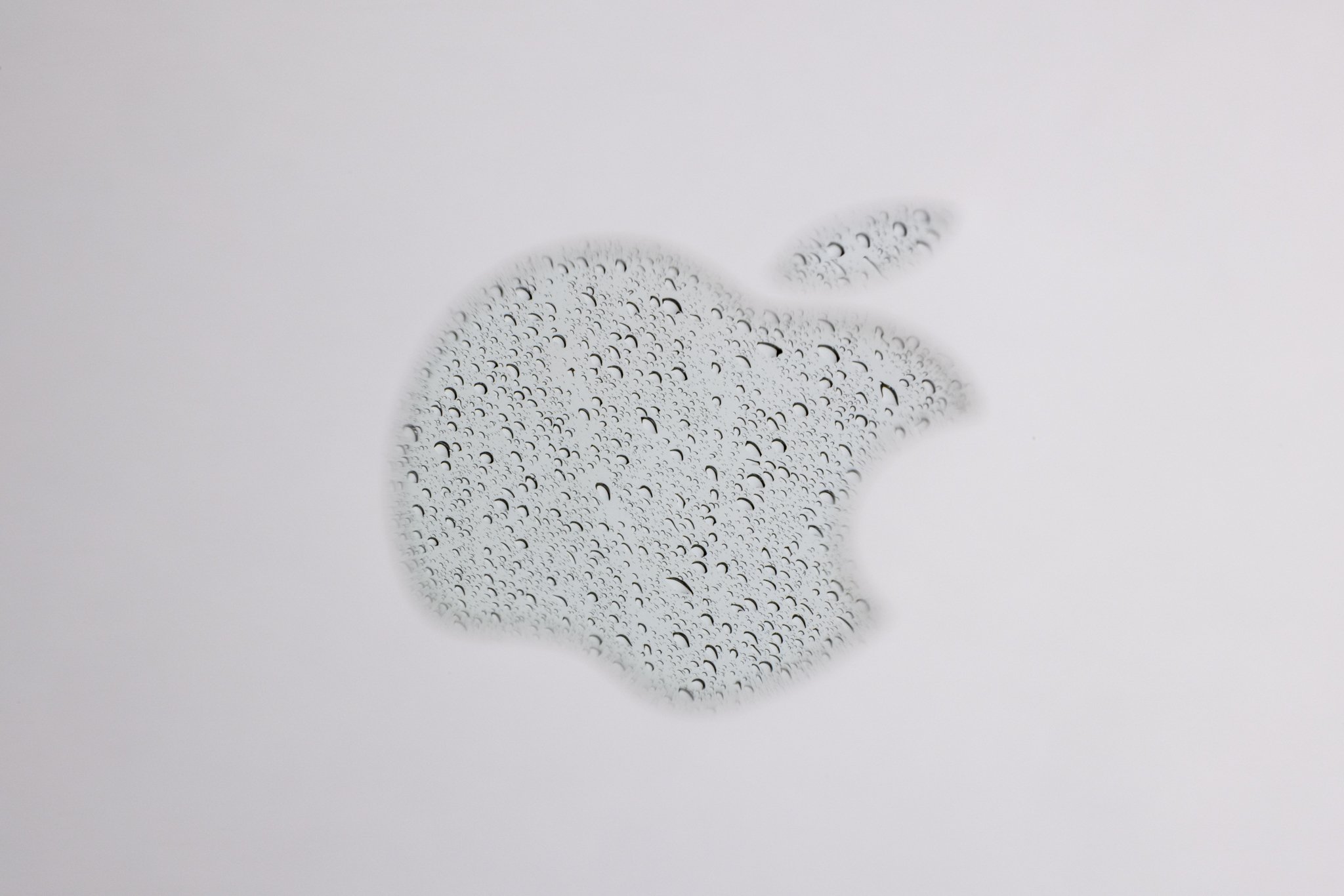 A reflection of rain in the Apple logo on a laptop photographed at f/32