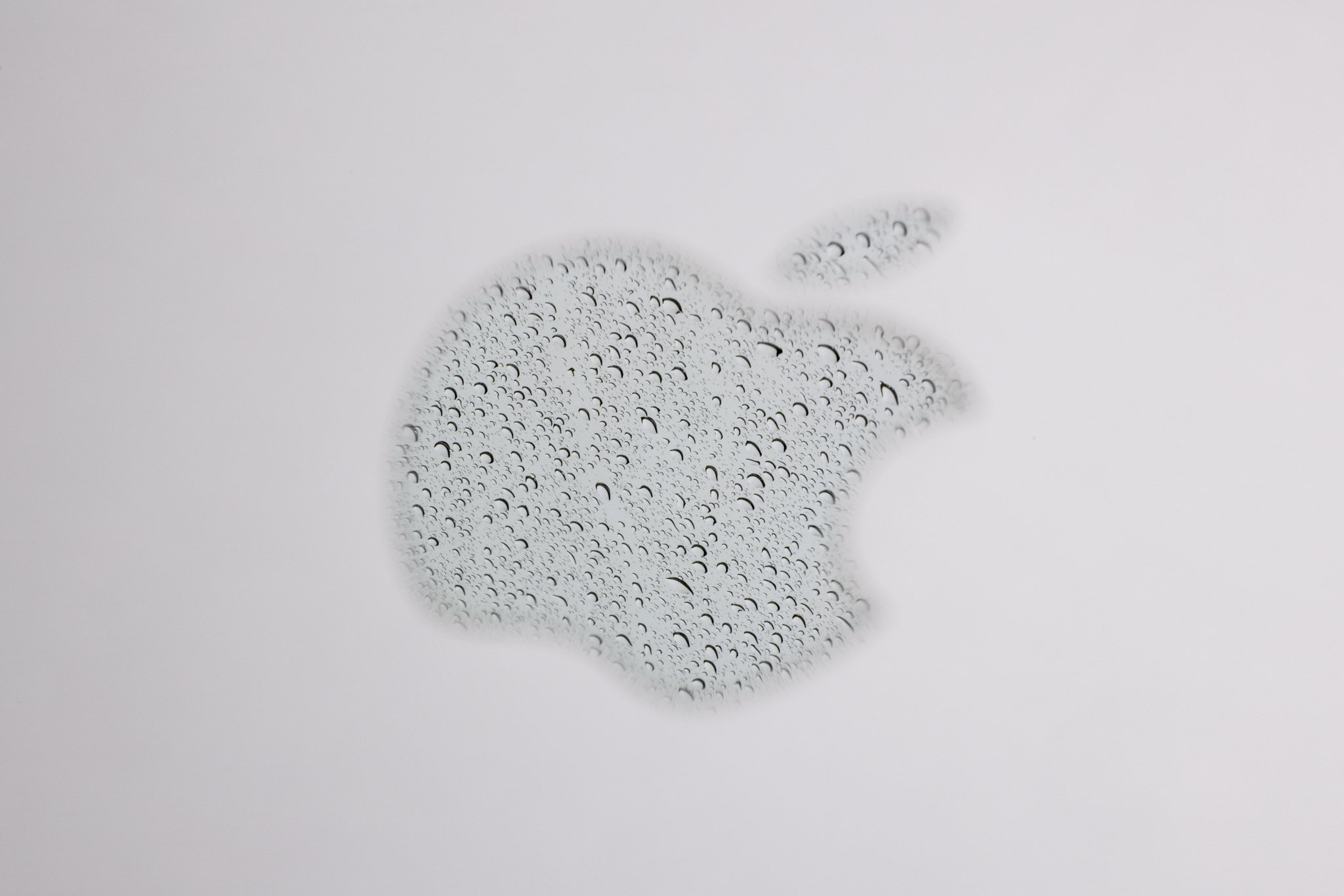 A reflection of rain in the Apple logo on a laptop photographed at f/29