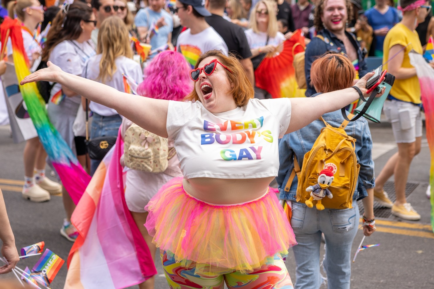 A happy person wearing heart-shaped sunglasses and a shirt that says 'Everybody's Gay'.