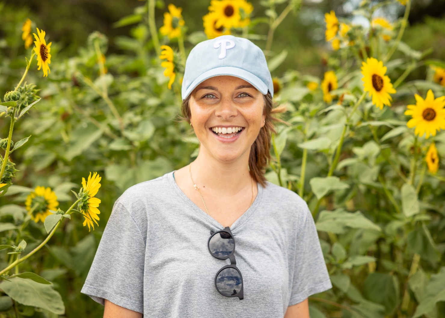 A woman smiling in front of a group of sunflowers.