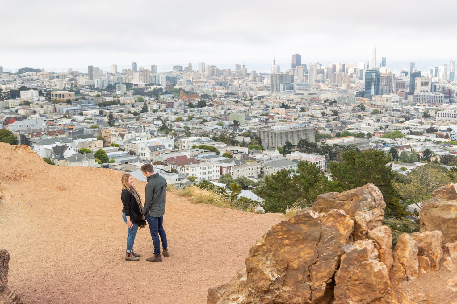 Two people standing close together overlooking the San Fransico skyline.