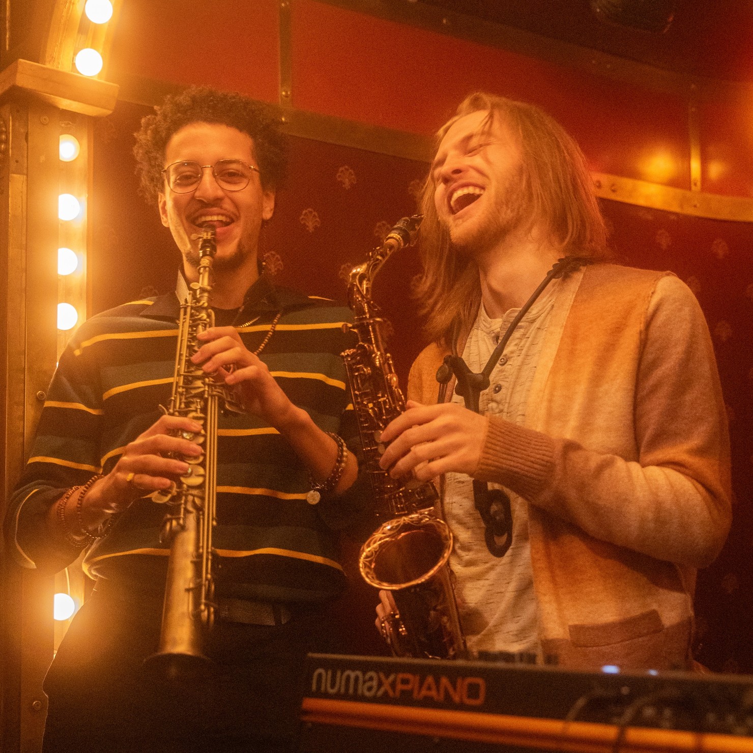Two saxophone players laughing.