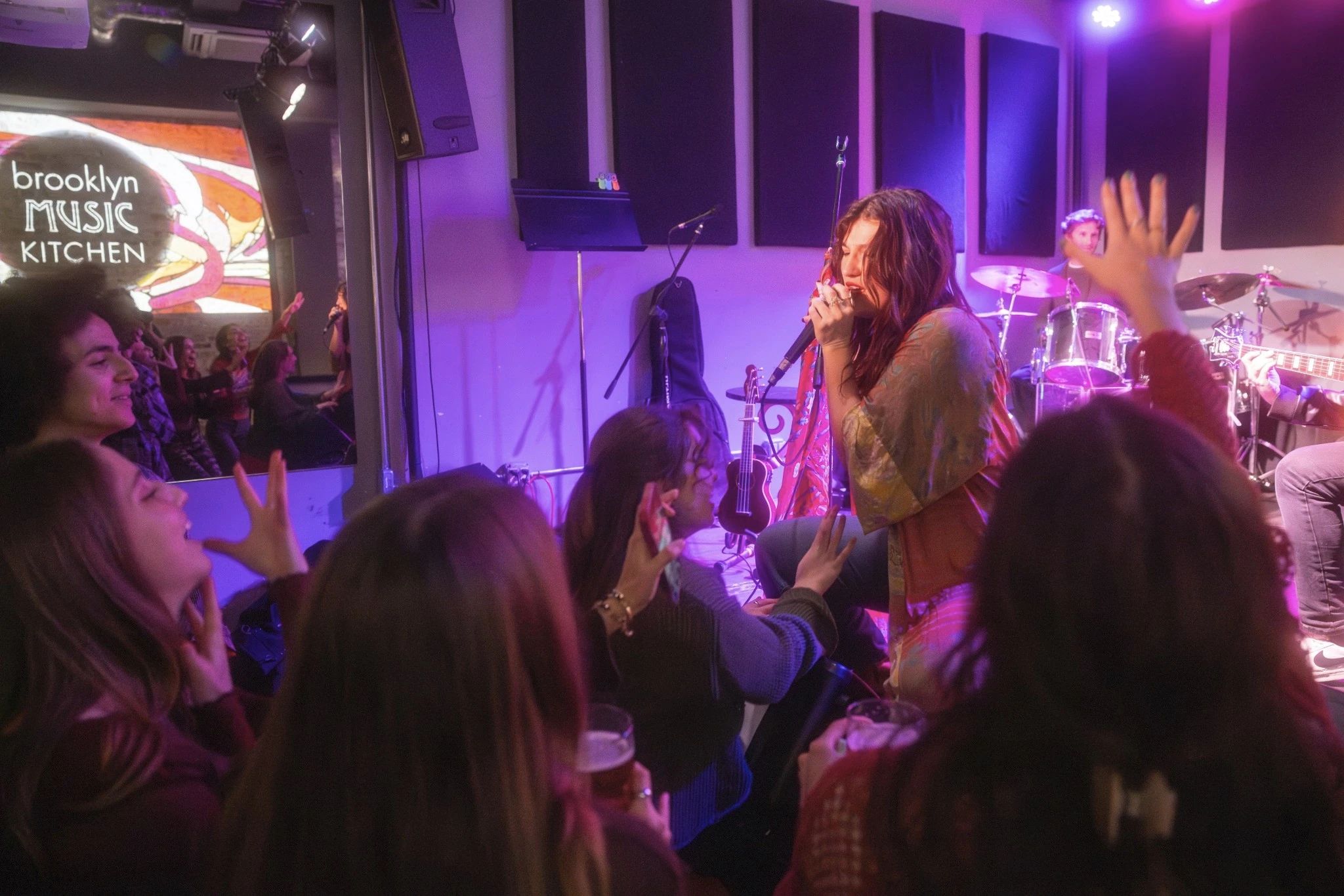 A crowd reaching for a woman singing on stage.