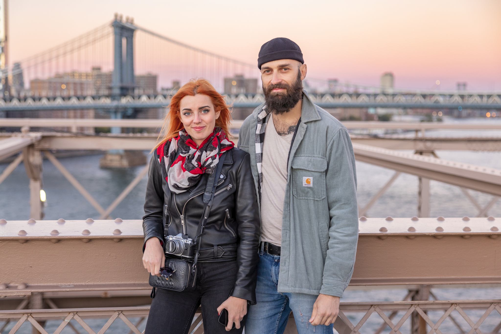 Two people standing on a bridge.