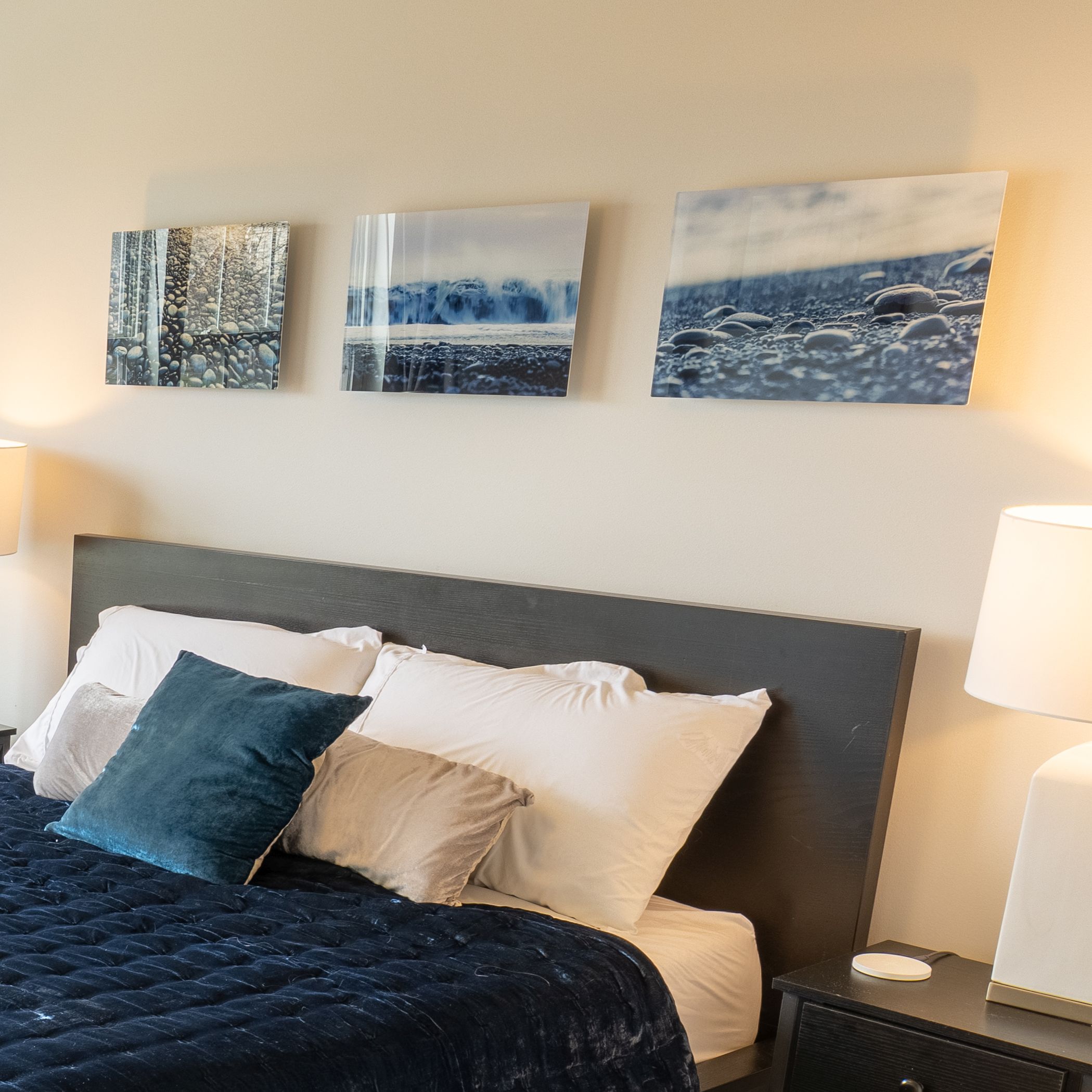 Three acrylic prints of the beach hanging over a bed