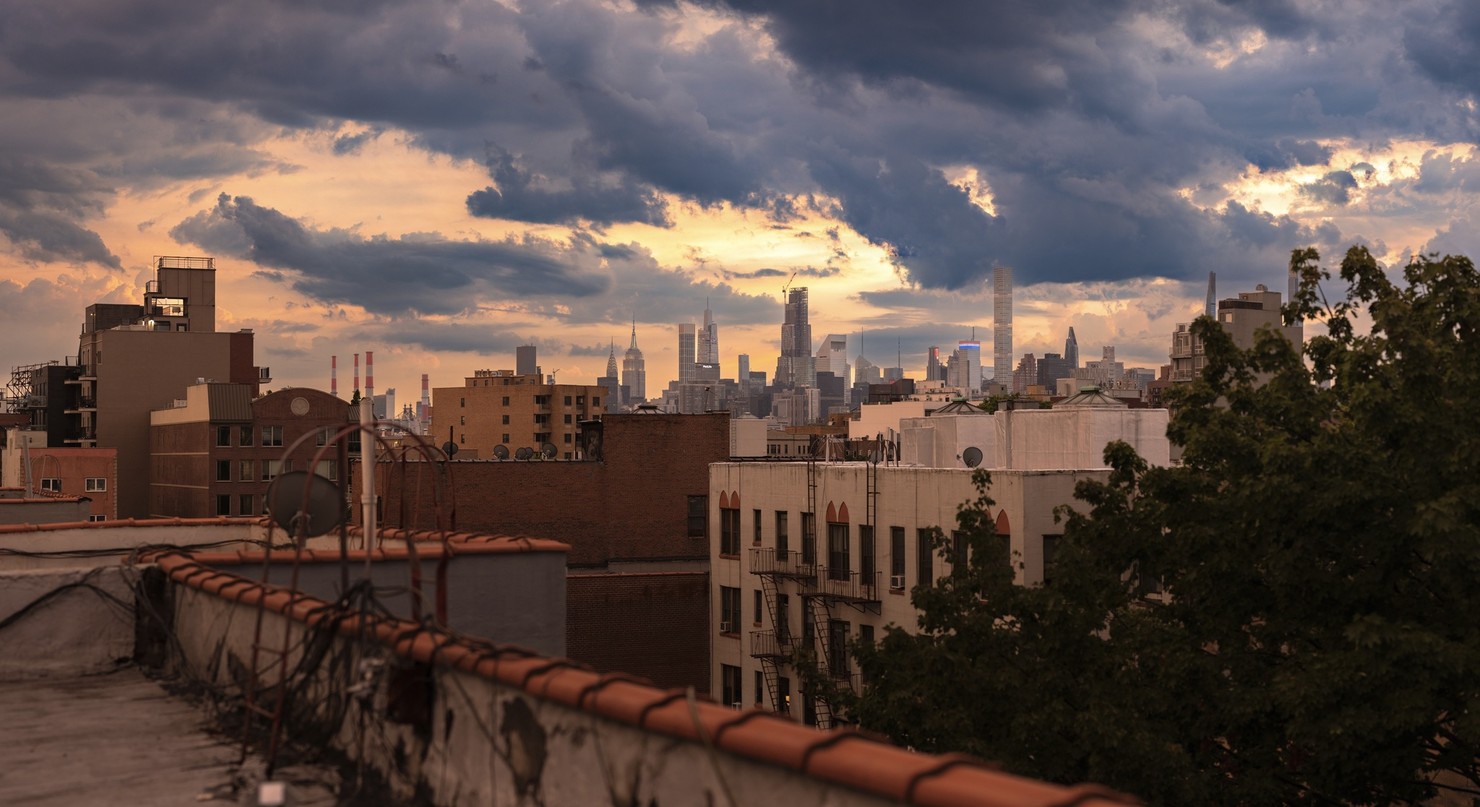 The Manhattan skyline at 8pm. The sky is cloudy and firey orange. It has just rained.